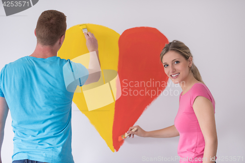 Image of couple are painting a heart on the wall