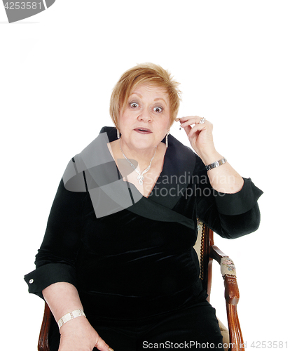 Image of Senior woman putting hearing aid on.