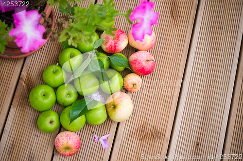 Image of Ripe apples with a leaf on a wooden surface, top view