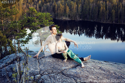 Image of middle age man with little cute son doing sport yoga on the top of the mountain together, happy family lifestyle people outdoor, summer wild nature for training