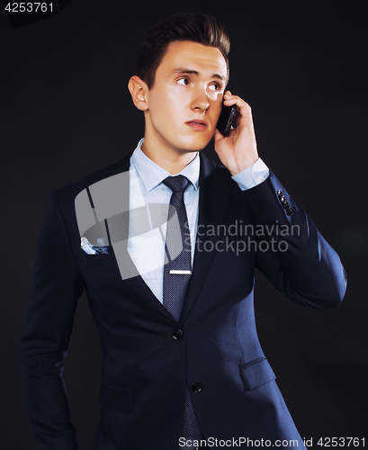 Image of young pretty business man standing on black background, modern h