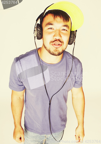 Image of young asian man in hat and headphones listening music on white b