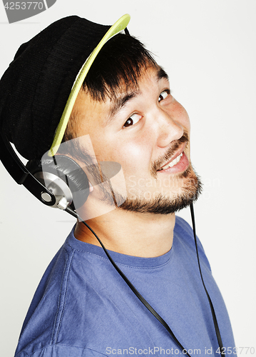 Image of young asian man in hat and headphones listening music on white b