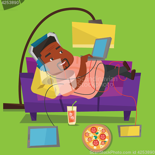 Image of Man lying on sofa with many gadgets.