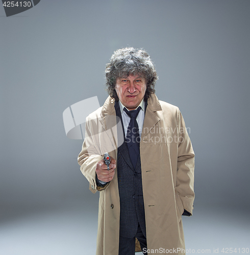 Image of Senior police agent with a gun on studio background