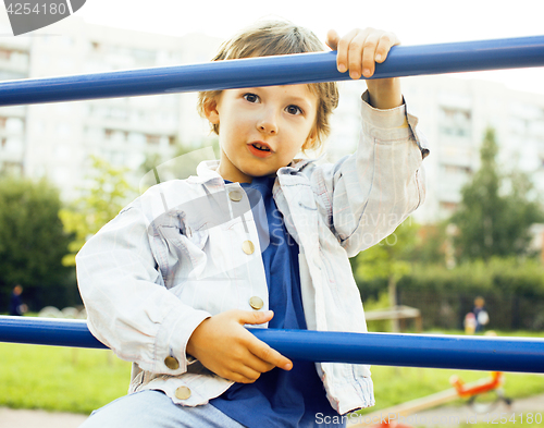 Image of little cute boy playing on playground, hanging on gymnastic ring