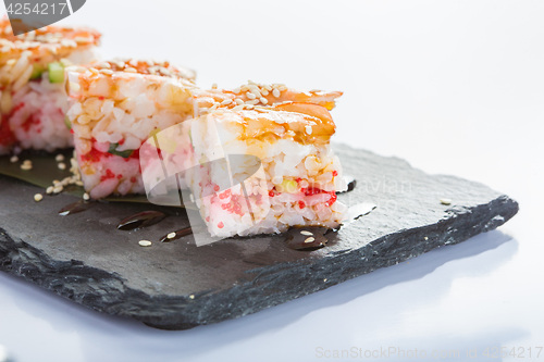 Image of set of sushi on a slate square plate. 