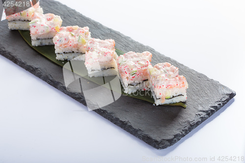 Image of set of sushi on a slate square plate. 