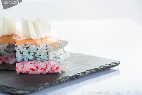 Image of set of sushi on a slate square plate. 