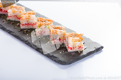 Image of set of sushi on a slate square plate. 