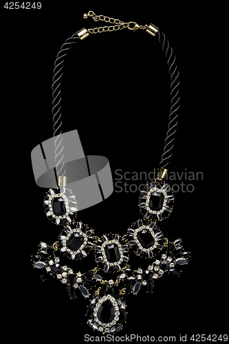 Image of necklace on a black background. gems. 