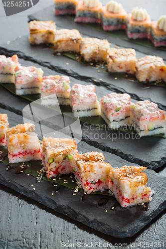 Image of set of sushi on a slate square plate. 