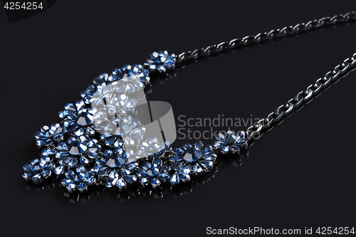 Image of blue necklace on a black background. gems. 