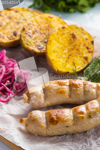 Image of macro meat kupaty with fries and greens on white plate