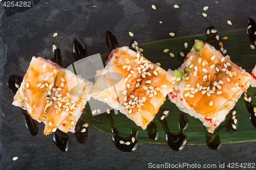 Image of set of sushi on a slate square plate. 