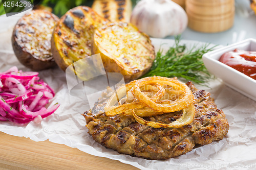 Image of burger grill with vegetables, sauce on a wooden surface. potatoes and bread