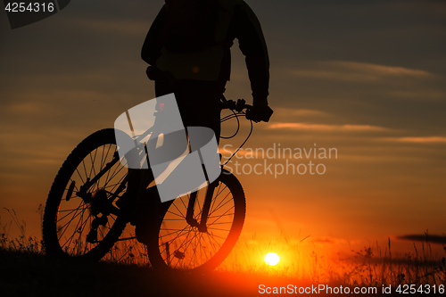 Image of Silhouette of a bike on sky background during sunset