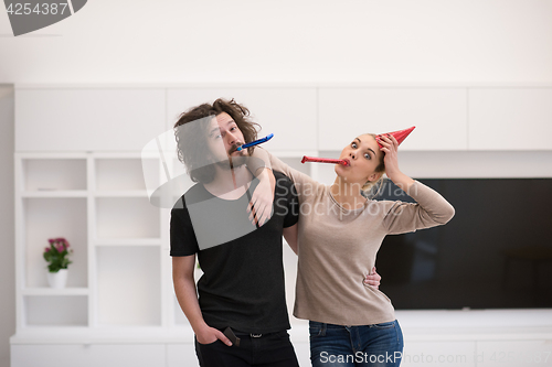 Image of couple in party hats blowing in whistle