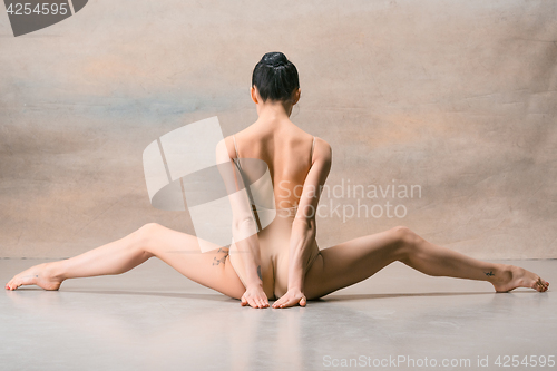 Image of The ballerina is sitting with her back legs wide apart