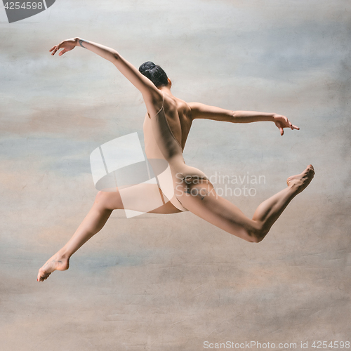 Image of Young beautiful modern style dancer jumping on a studio background