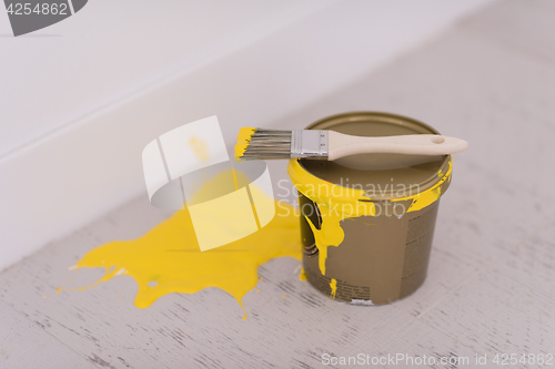 Image of Yellow paint tin can with brush on top