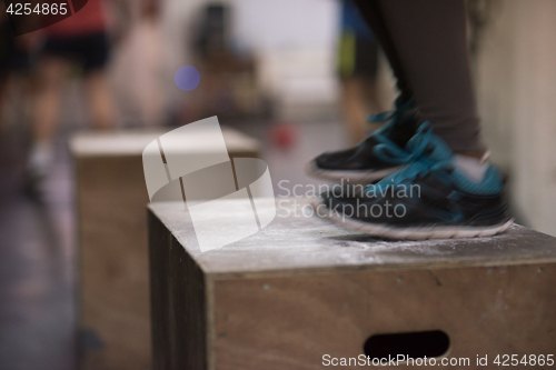 Image of black woman is performing box jumps at gym