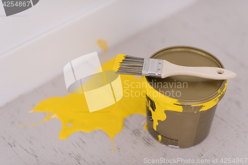 Image of Yellow paint tin can with brush on top