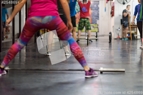 Image of a group of people exercise with an empty bar