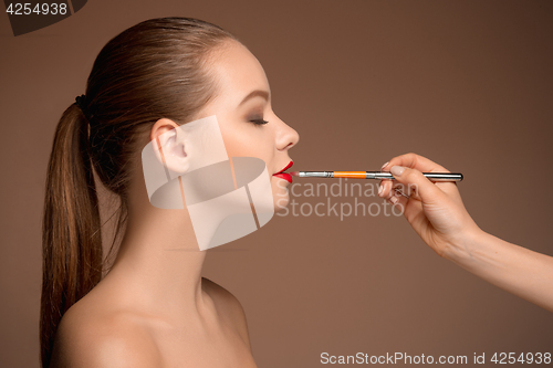 Image of Beautiful female lips with make-up and brush