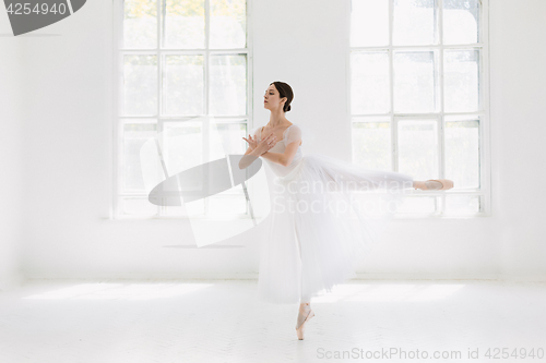 Image of Young and incredibly beautiful ballerina is posing and dancing in a white studio