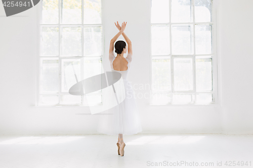 Image of Young and incredibly beautiful ballerina is posing and dancing in a white studio