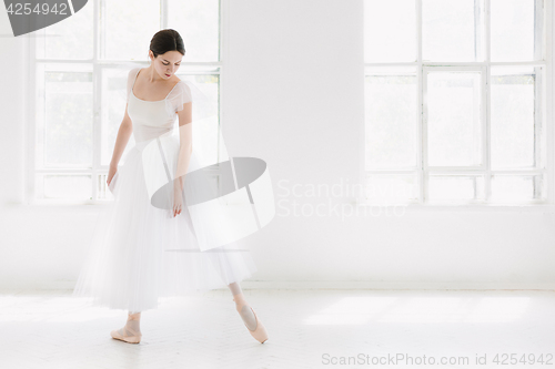 Image of Young and incredibly beautiful ballerina is posing and dancing in a white studio