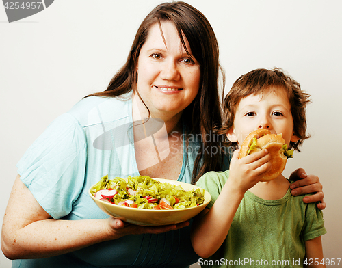 Image of mature woman holding salad and little cute boy with hamburger te