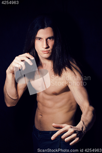 Image of handsome young man with long hair naked torso on black backgroun