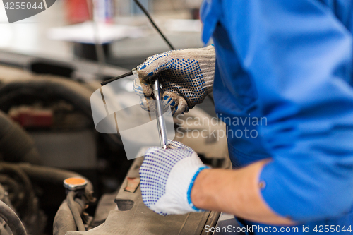 Image of mechanic man with wrench repairing car at workshop