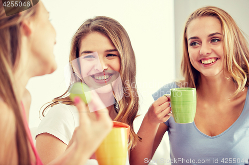 Image of happy young women drinking tea with sweets at home