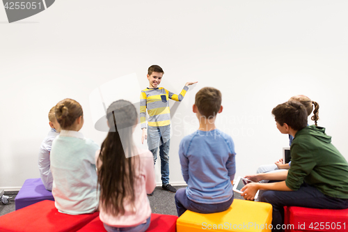 Image of happy student boy showing something at white wall