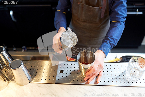 Image of bartender with ice and shaker at cocktail bar