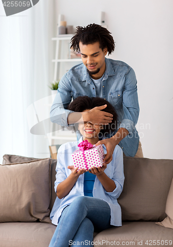 Image of happy couple with gift box at home