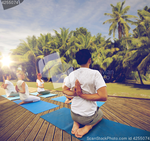 Image of group of people making yoga exercises outdoors