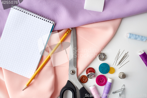 Image of scissors, sewing tools, cloth and notepad