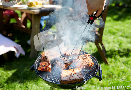 Image of man cooking meat on barbecue grill at summer party