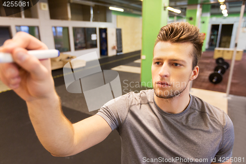 Image of man writing note to whiteboard in gym