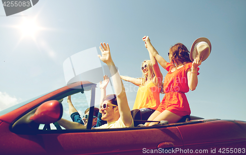 Image of happy friends driving in cabriolet car at country