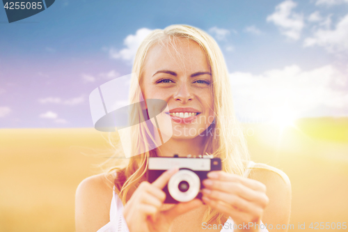 Image of happy young woman with film camera outdoors