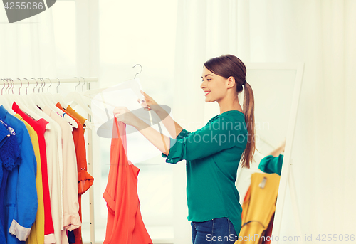 Image of happy woman choosing clothes at home wardrobe