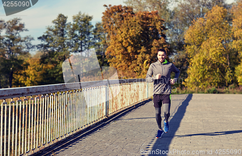 Image of happy young man running over city bridge