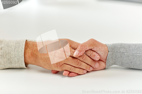 Image of close up of old man and young woman holding hands