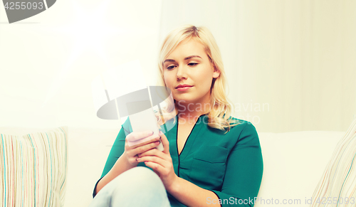 Image of happy woman with smartphone at home