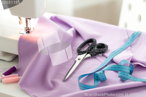 Image of sewing machine, scissors, tape measure and fabric